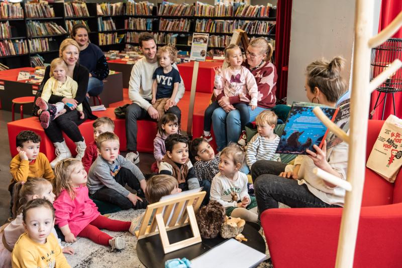 ouders en kinderen luisteren naar voorlezer